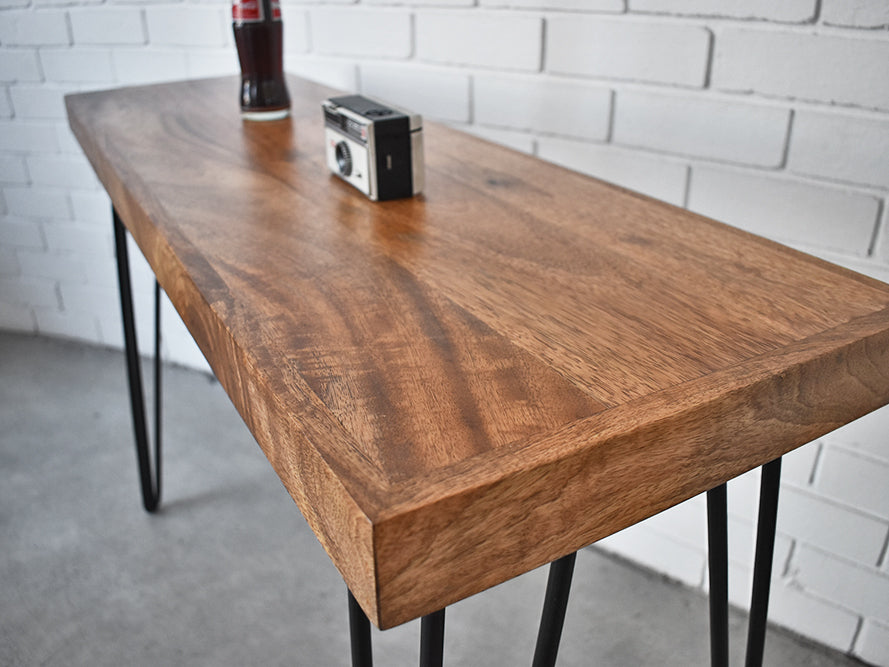 Wooden table with black metal legs against a white brick wall.